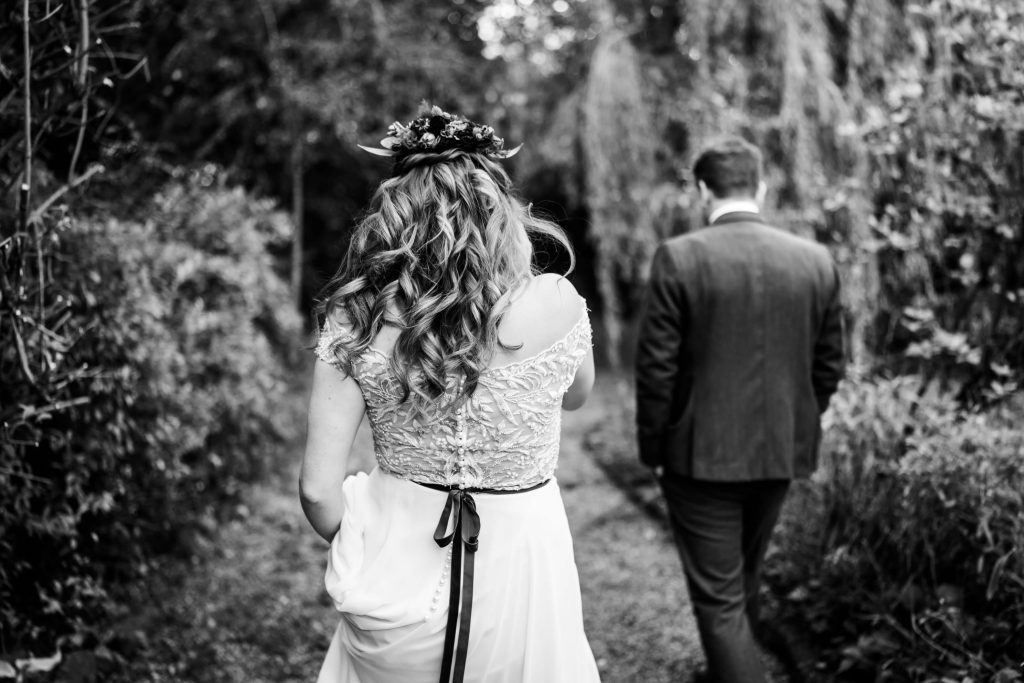 Bride and groom walking in garden, black and white photo.
