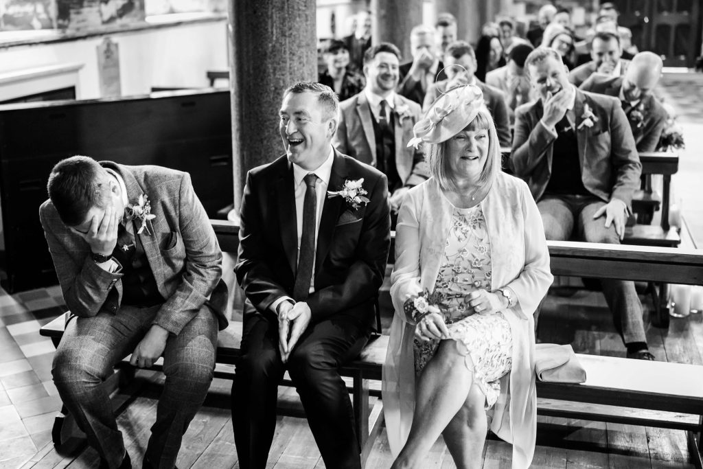 Joyful wedding guests laughing during ceremony.