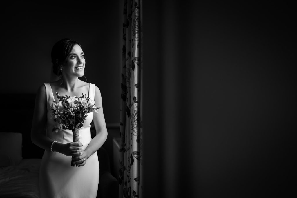 Elegant bride holding bouquet, black and white portrait.