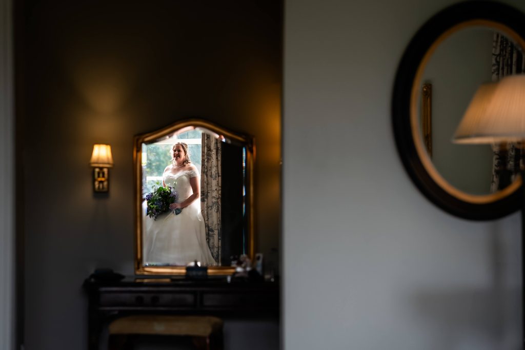 Bride reflected in mirror holding bouquet.