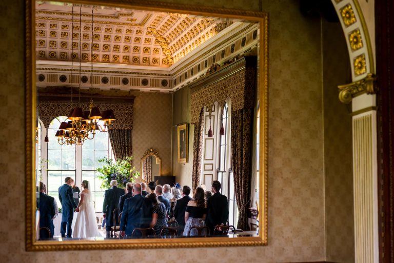 Elegant wedding ceremony reflected in ornate mirror.