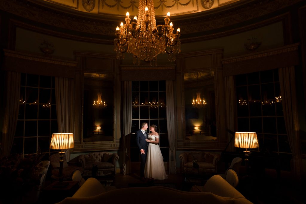 Couple embracing under chandeliers at Swinton Park