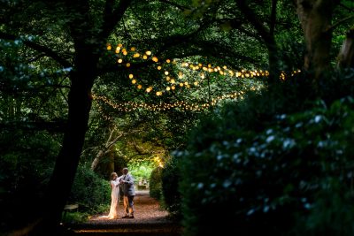 Couple dancing under twinkling lights on forest pathway at Hazlewood Castle