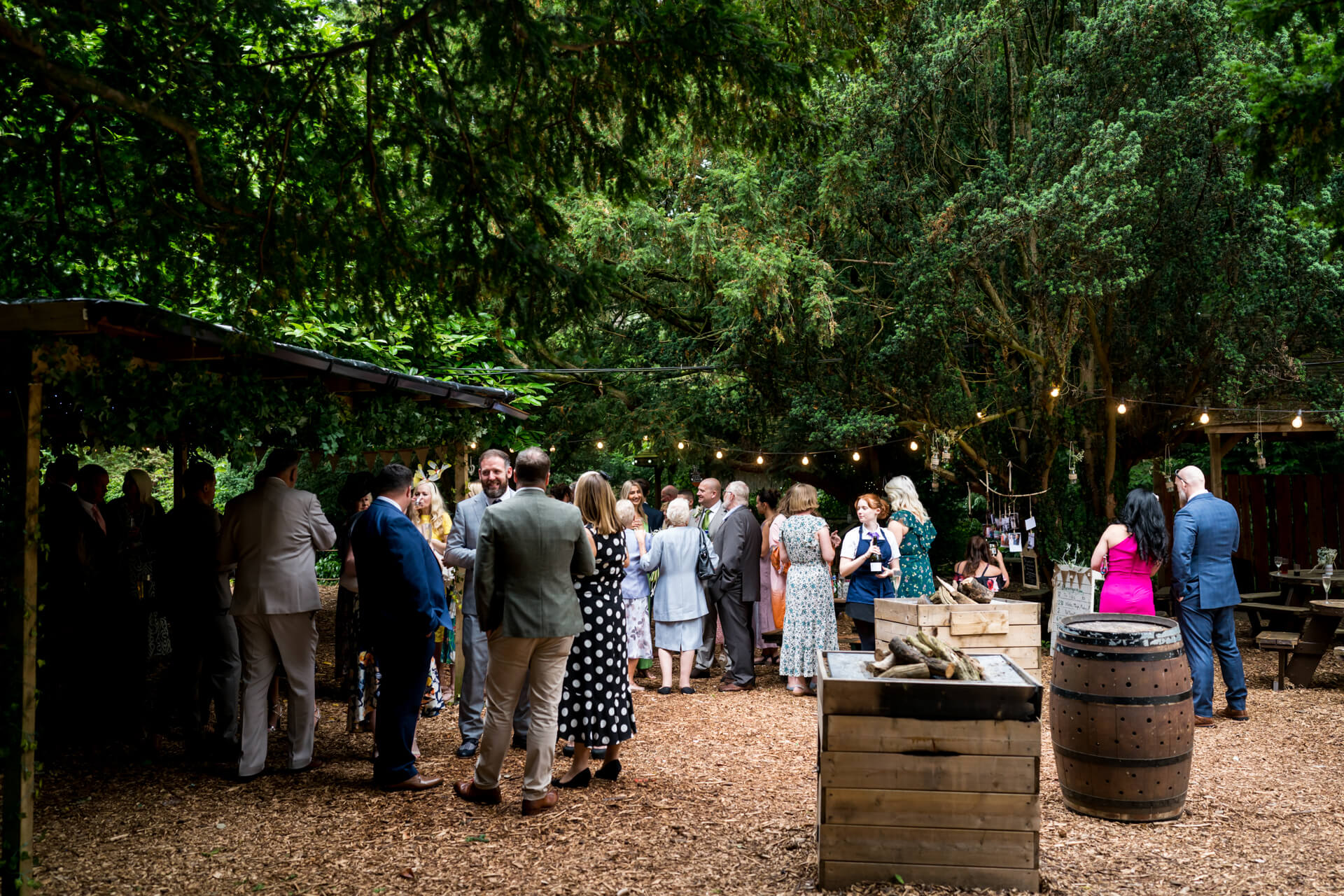 Outdoor woodland wedding with string lights and guests.