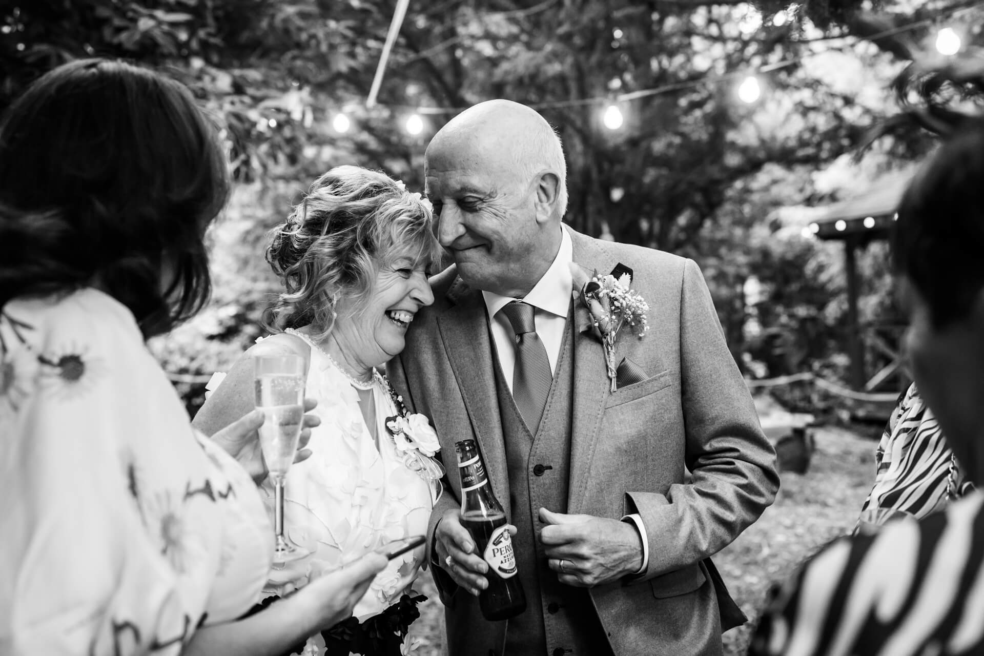 Joyful couple sharing a laugh at wedding reception.