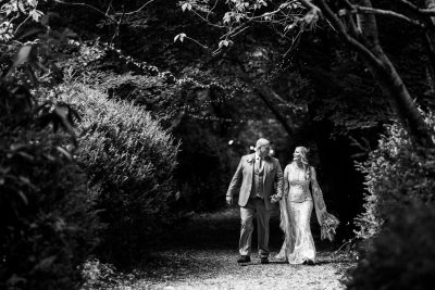 Couple walking in forest aisle, wedding day, black and white.
