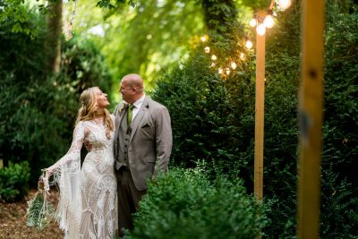 Bride and groom smiling in forest wedding with lights.