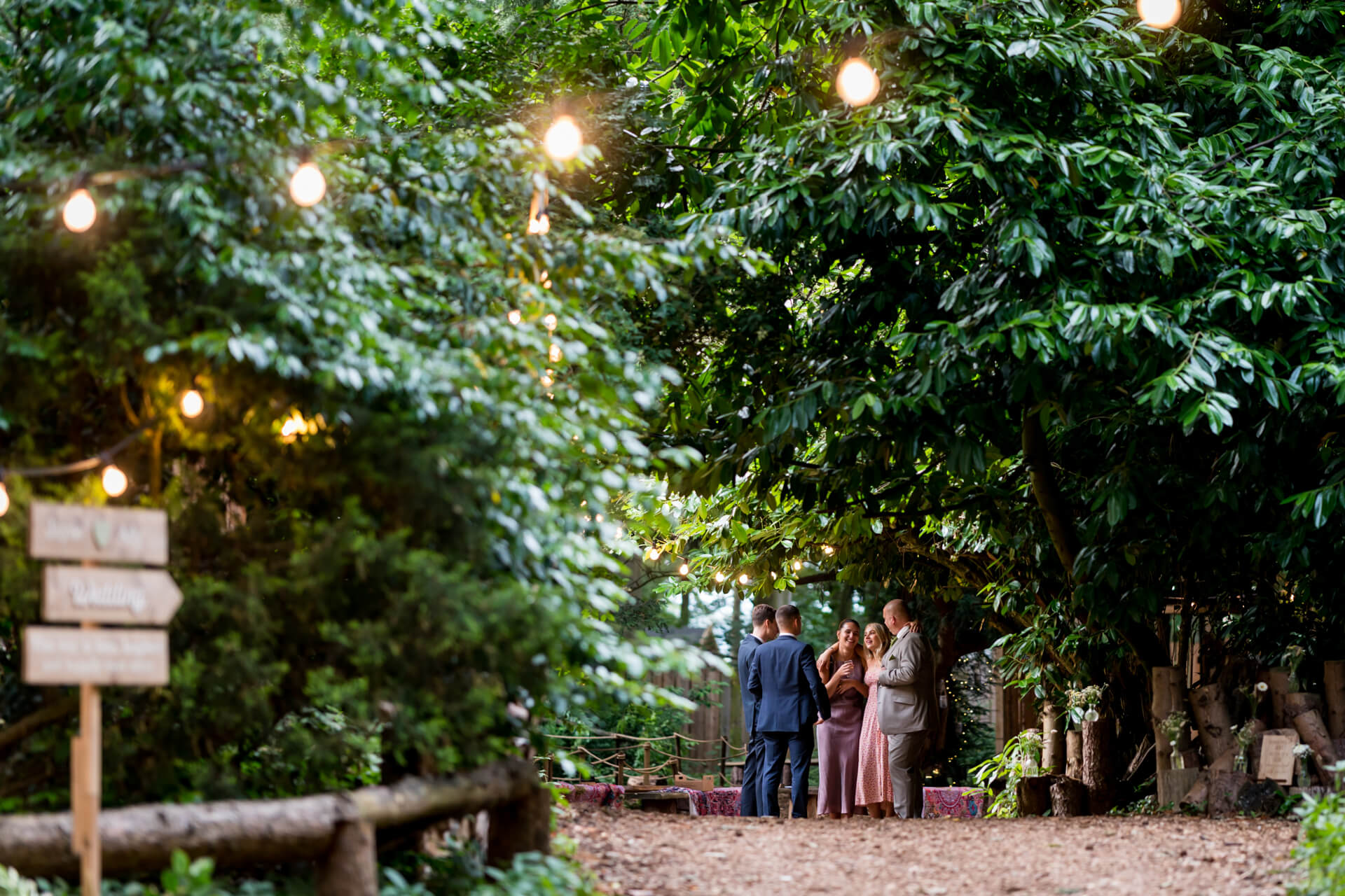 Couple and guests at forest pathway wedding.