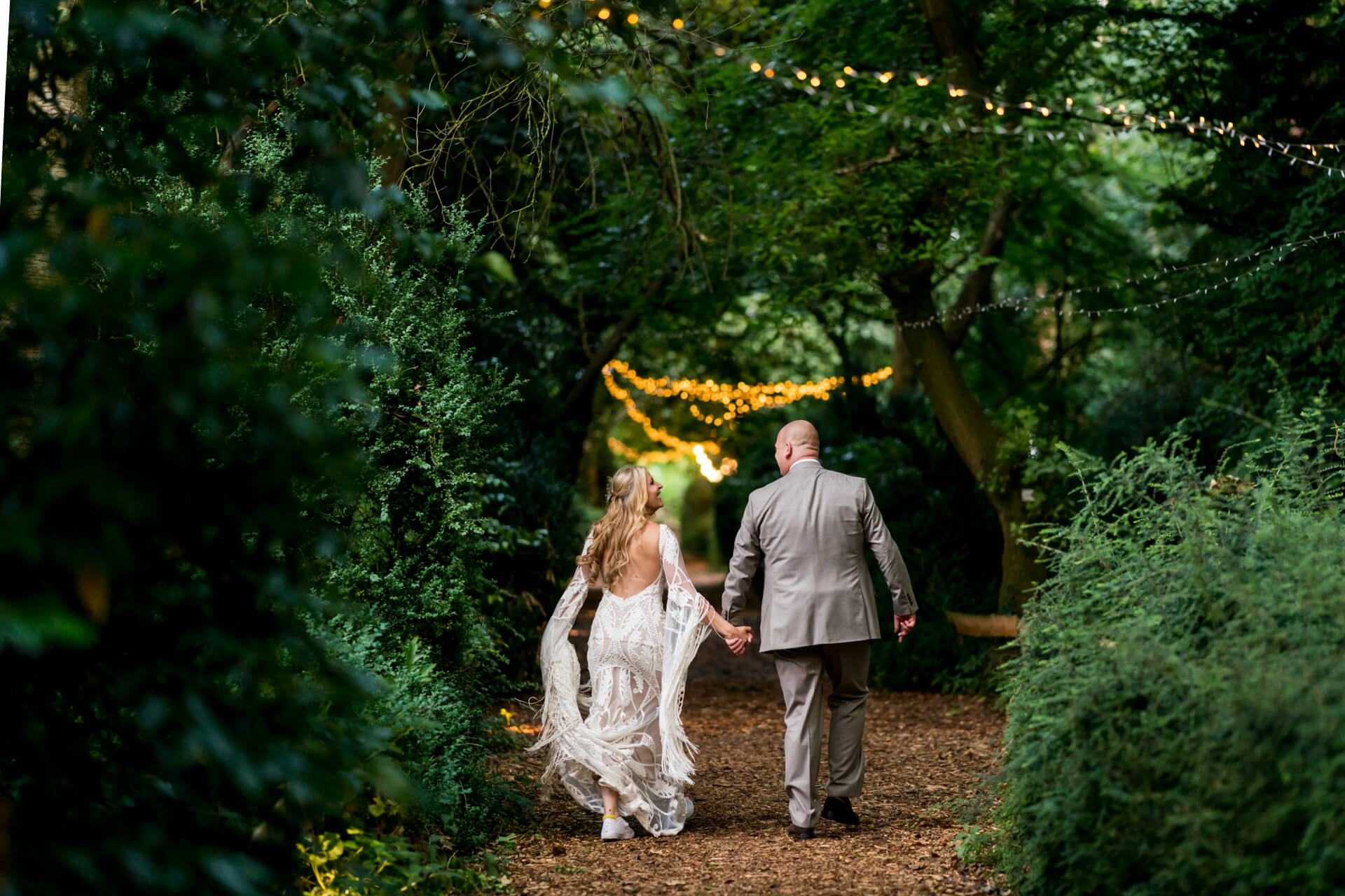 Bride and groom walking in forest pathway at Hazlewood Castle
