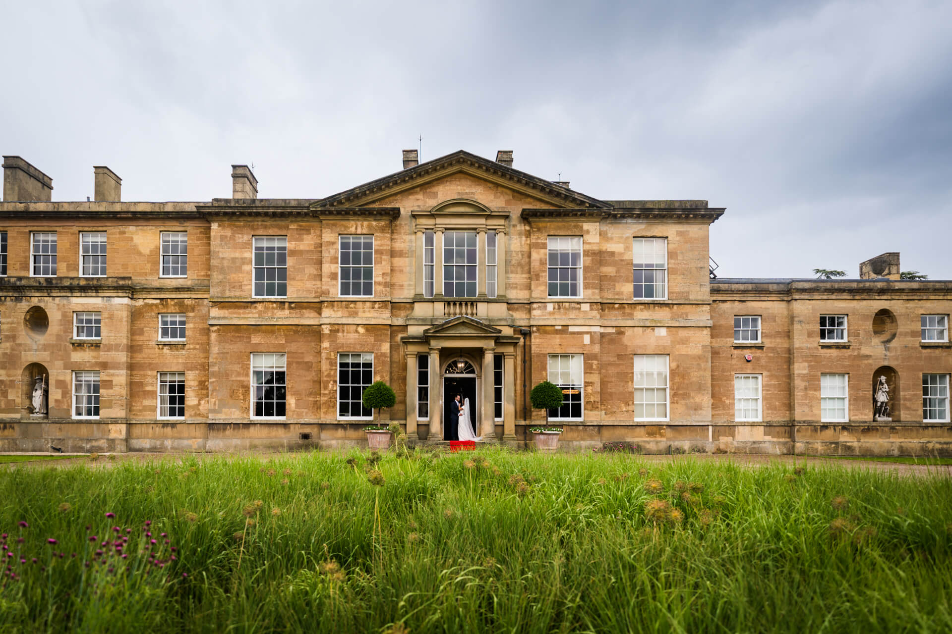 Elegant Bowcliffe Hall with couple at entrance.