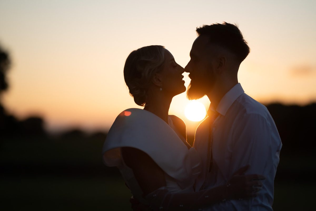 Wedding couple kissing at sunset silhouette