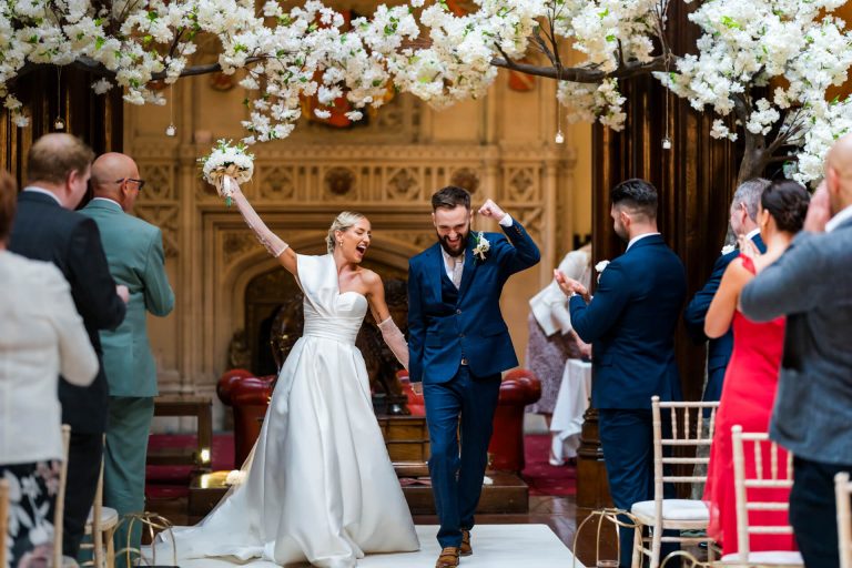Joyful wedding couple celebrating at the top of the aisle at Allerton Castle