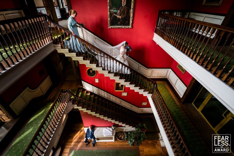 Wedding party on ornate red staircase in grand hall