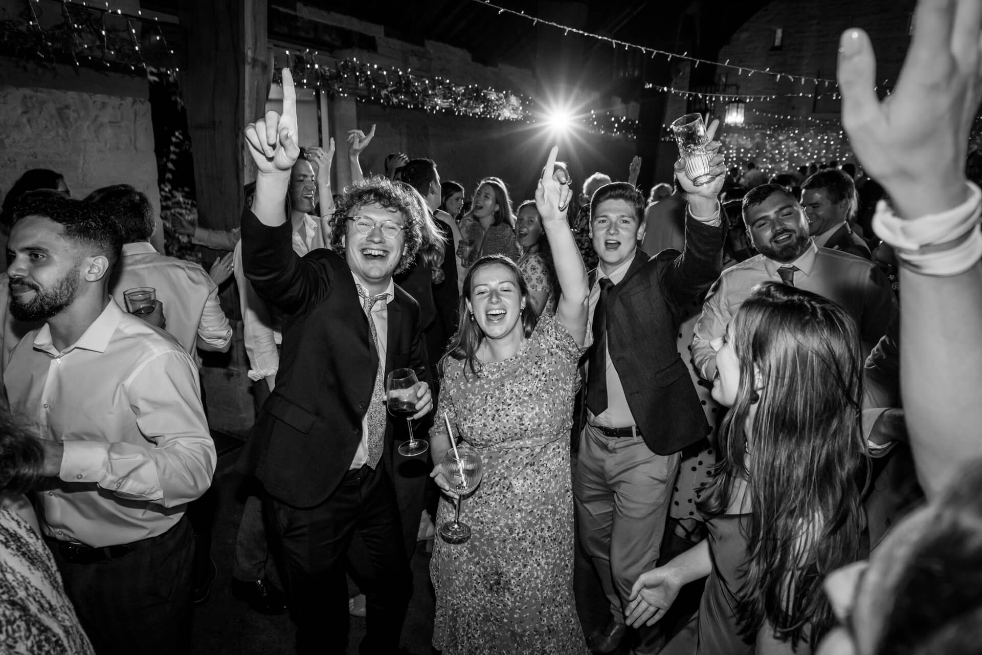 Joyful wedding guests dancing at evening reception