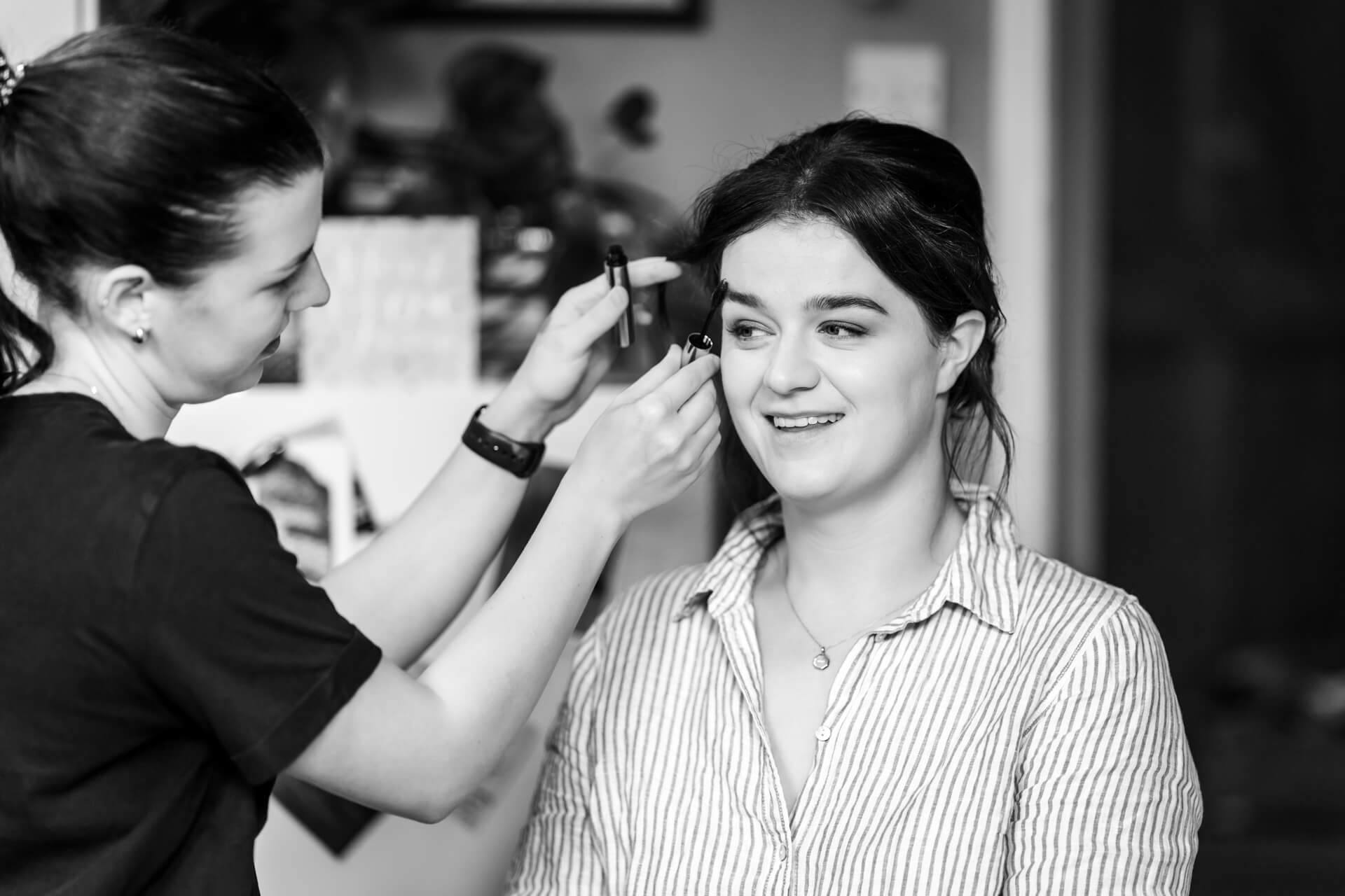 Makeup artist applying makeup to smiling woman