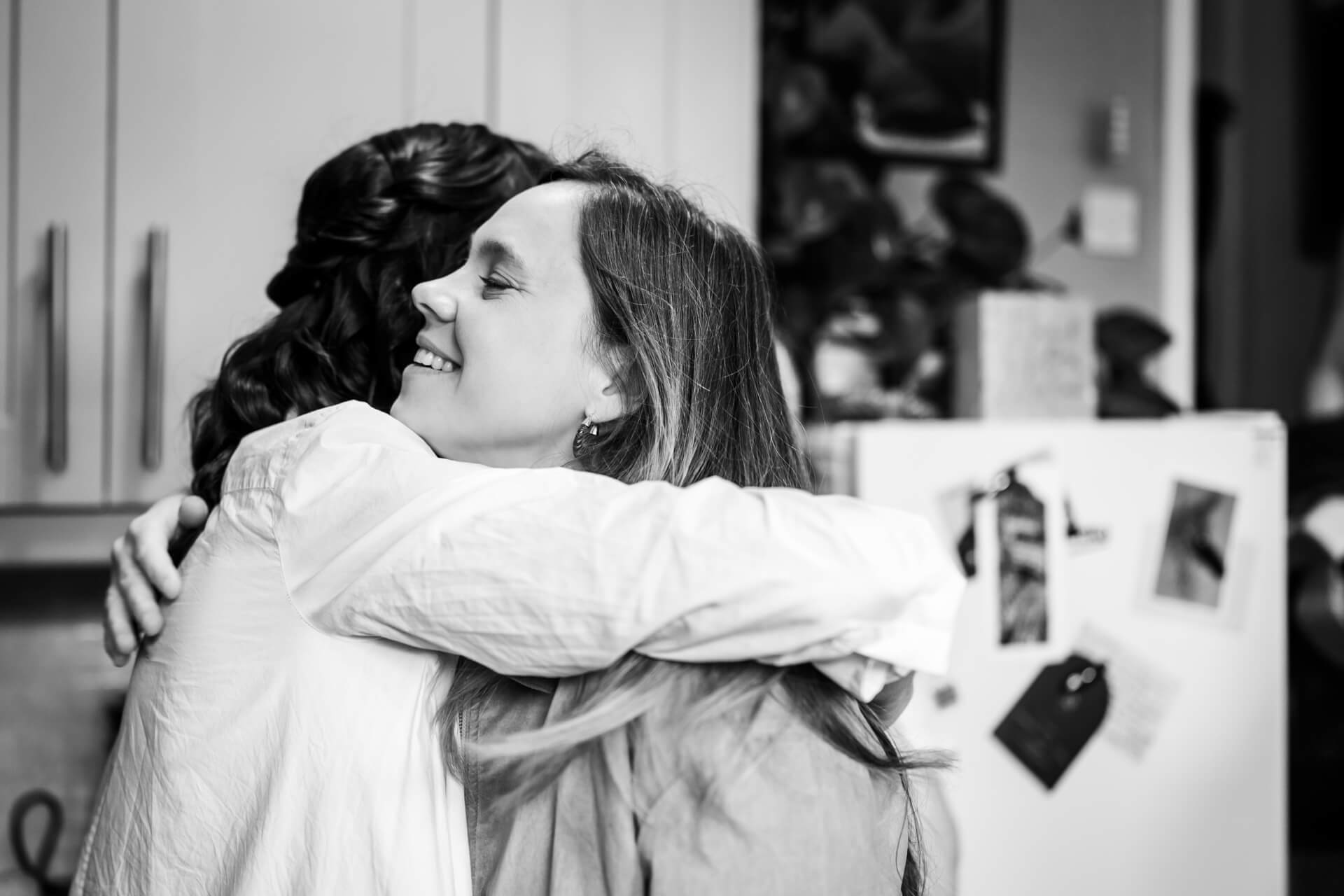 Two women embracing happily in a kitchen
