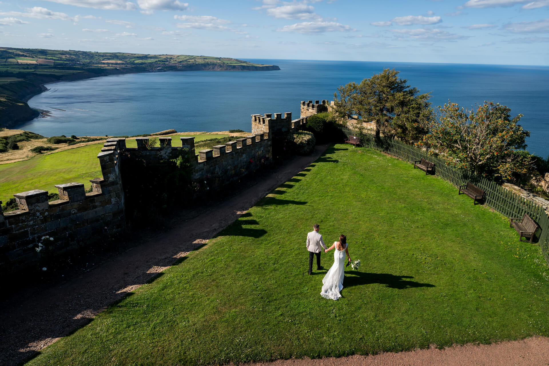 Wedding couple walking near castle overlooking sea