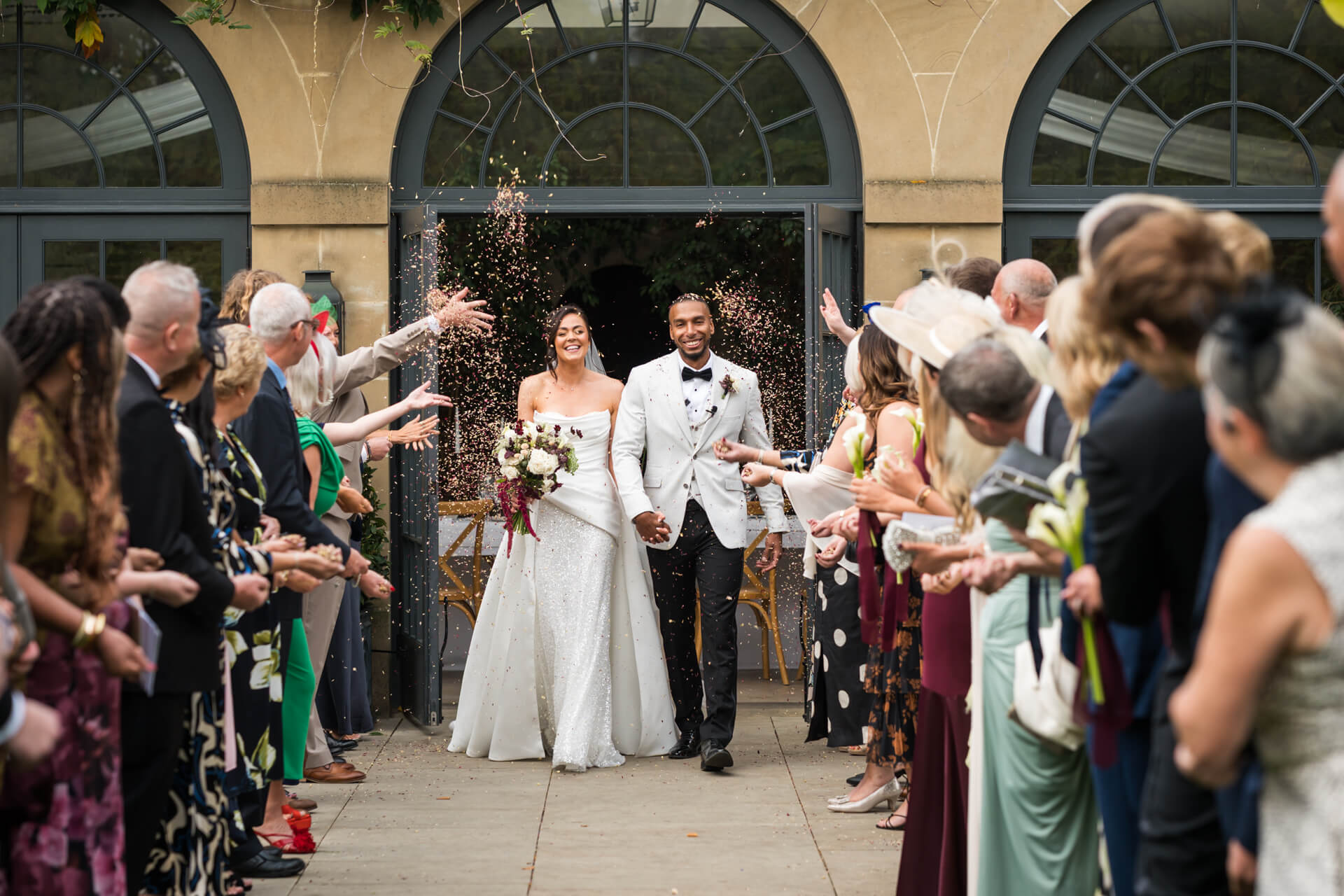 Bride and groom exit to cheering crowd.