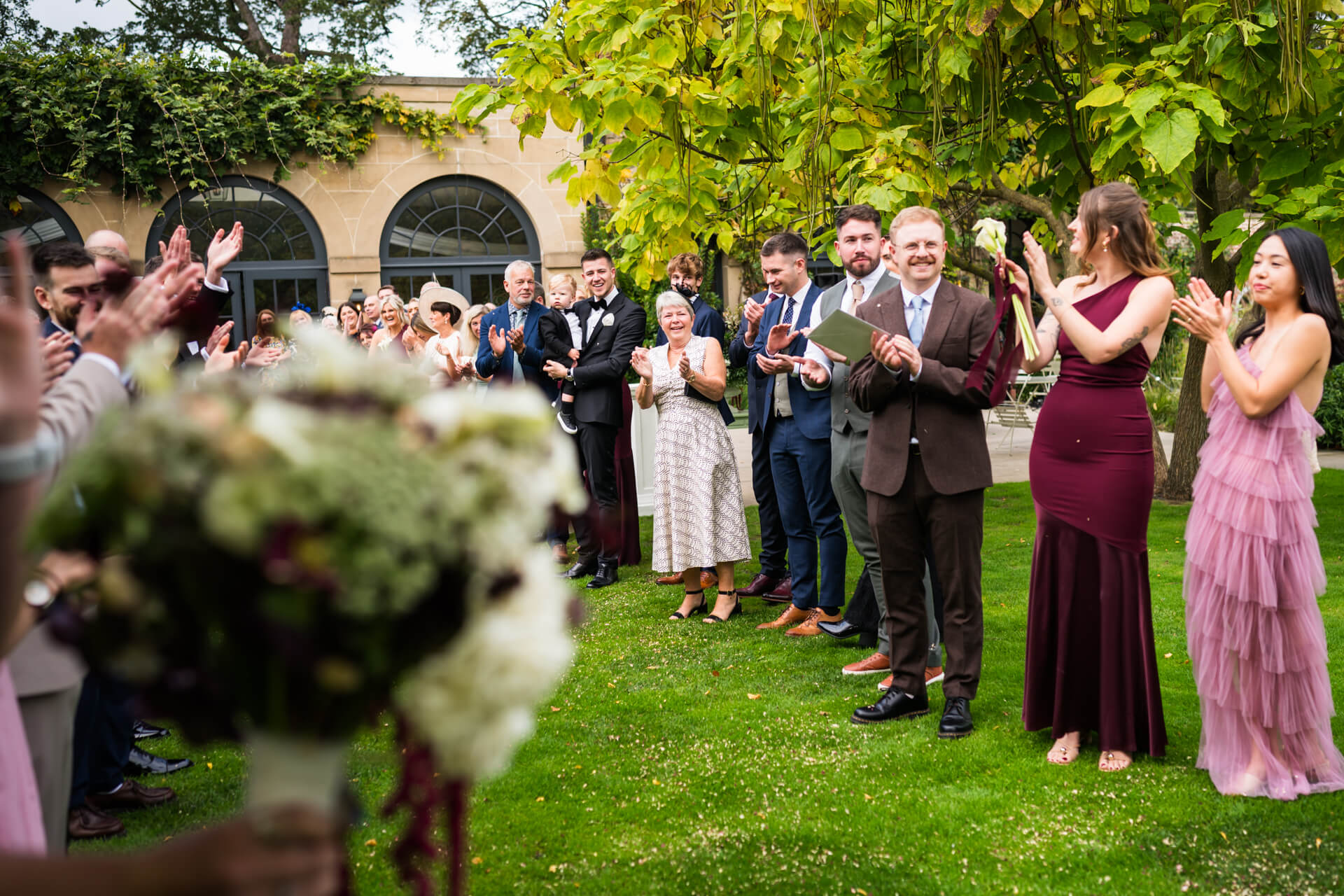 Guests clapping outdoors at a wedding ceremony.