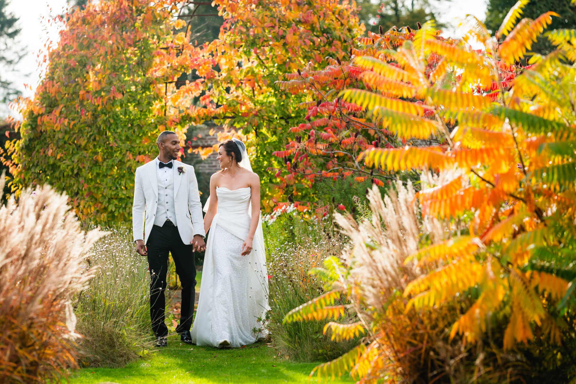 Wedding couple walking in autumn garden.