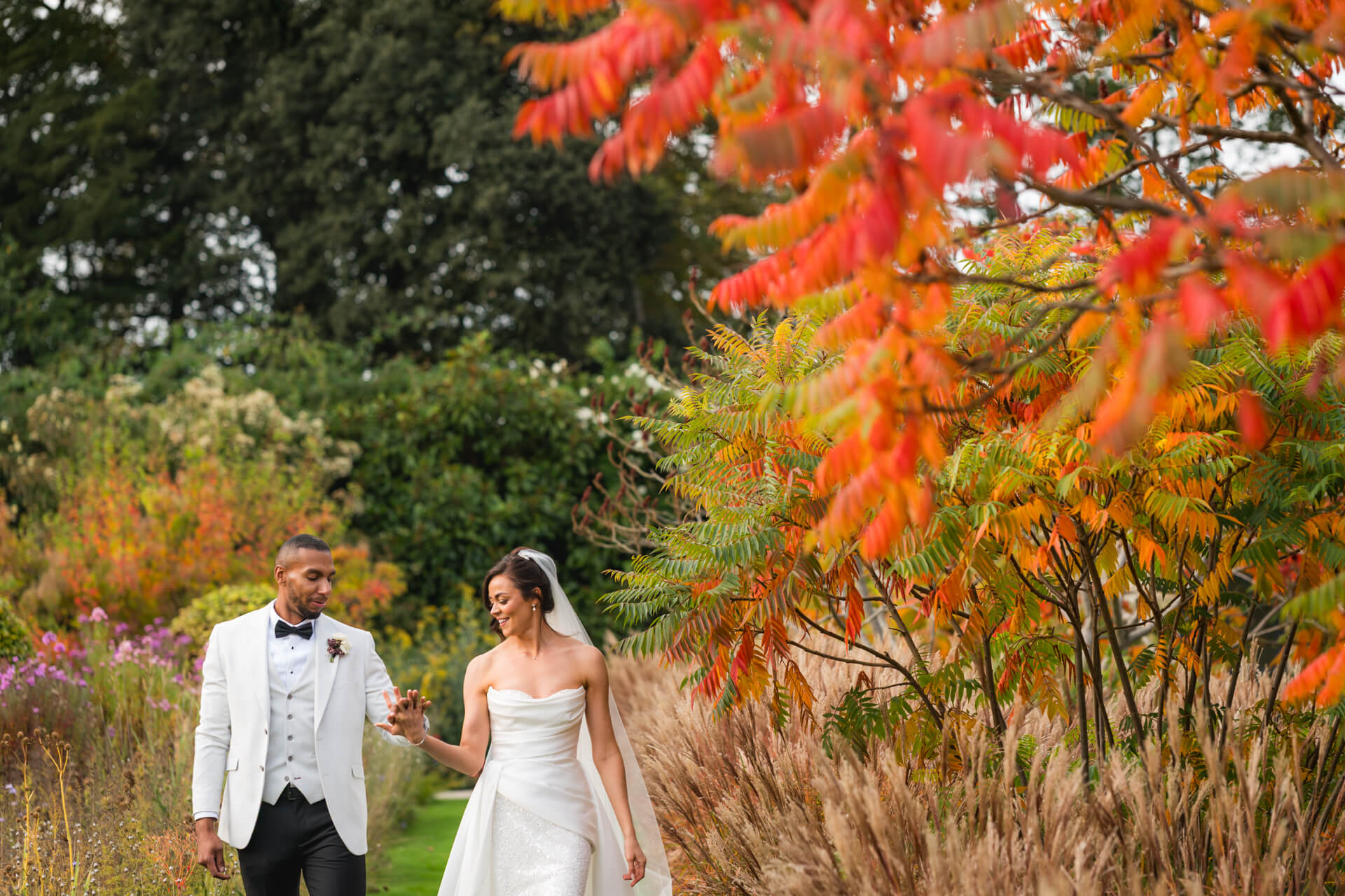 Bride and groom walking in autumn garden
