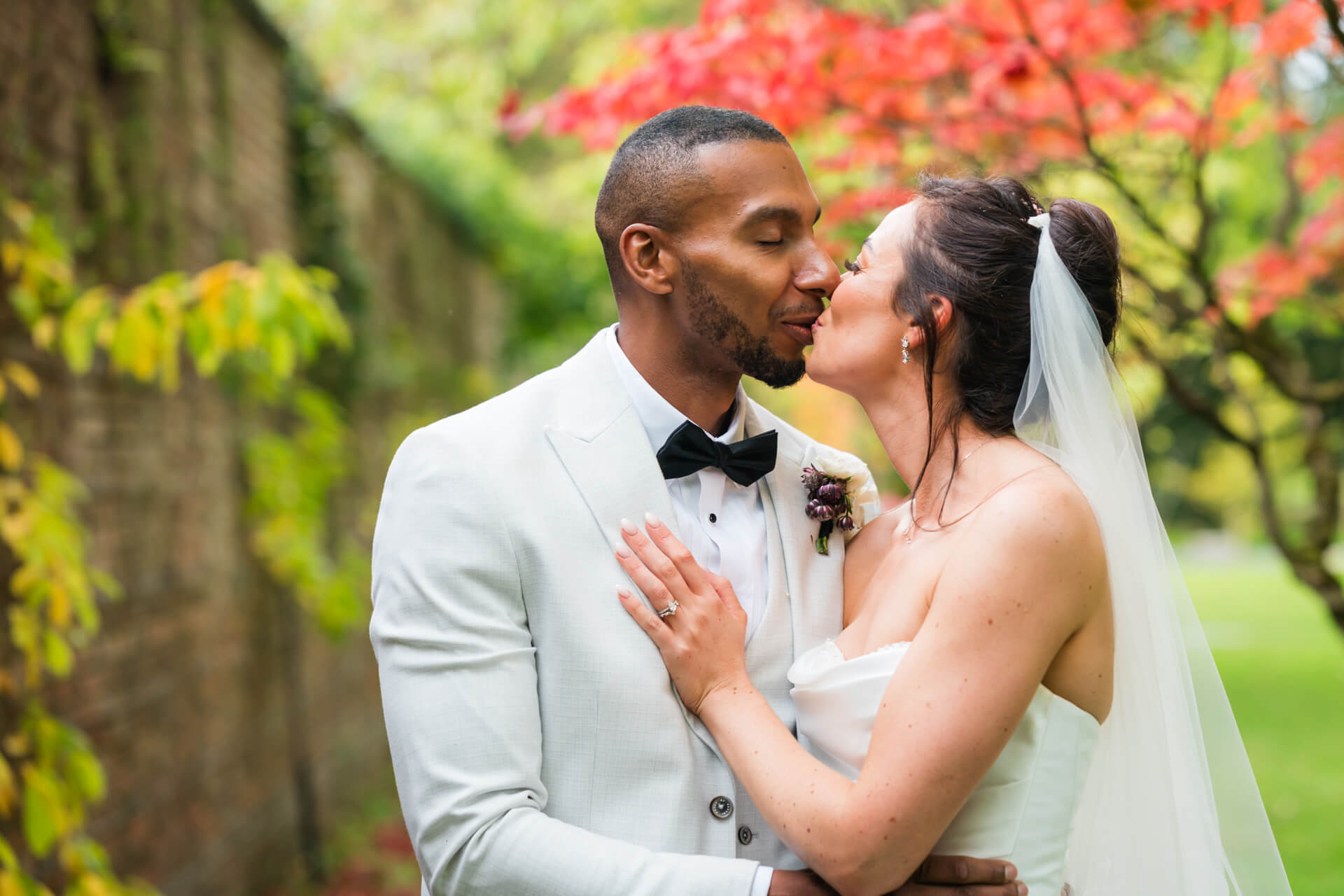 Bride and groom kissing in a garden.
