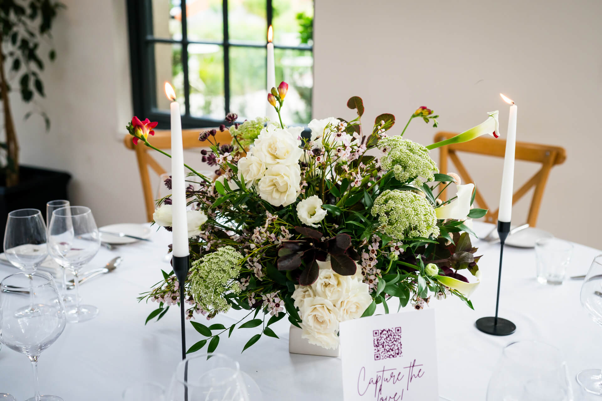 Elegant floral centrepiece with candles on dining table.