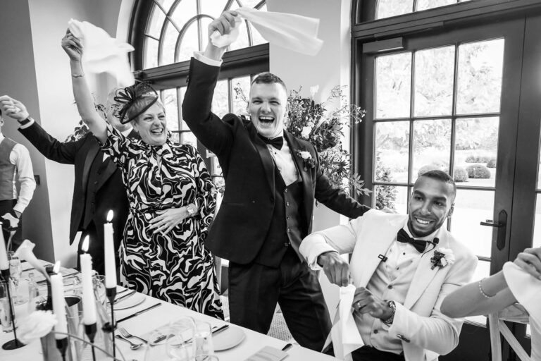 People celebrating at a formal event, smiling and waving.