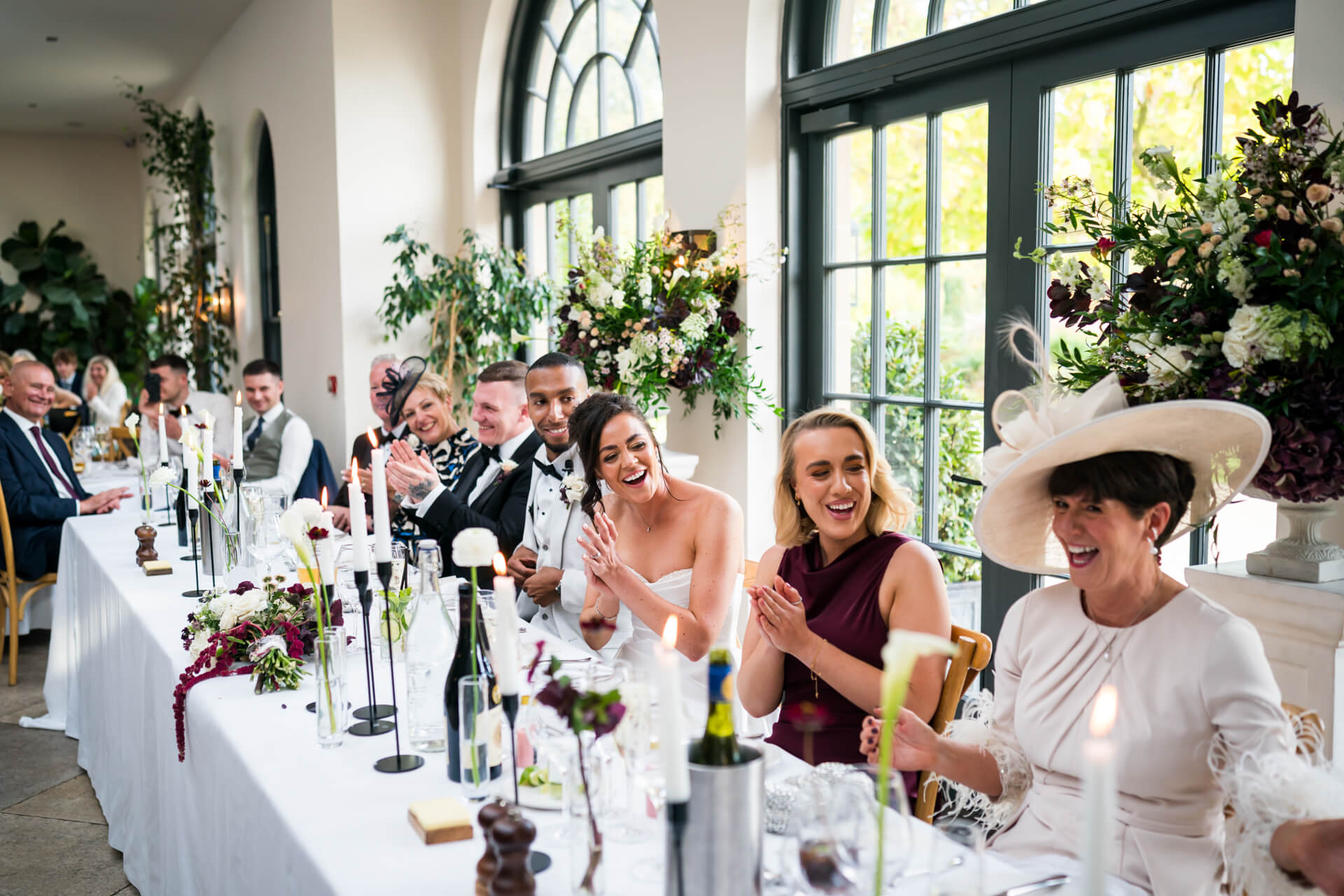 Wedding guests clapping and smiling at reception.