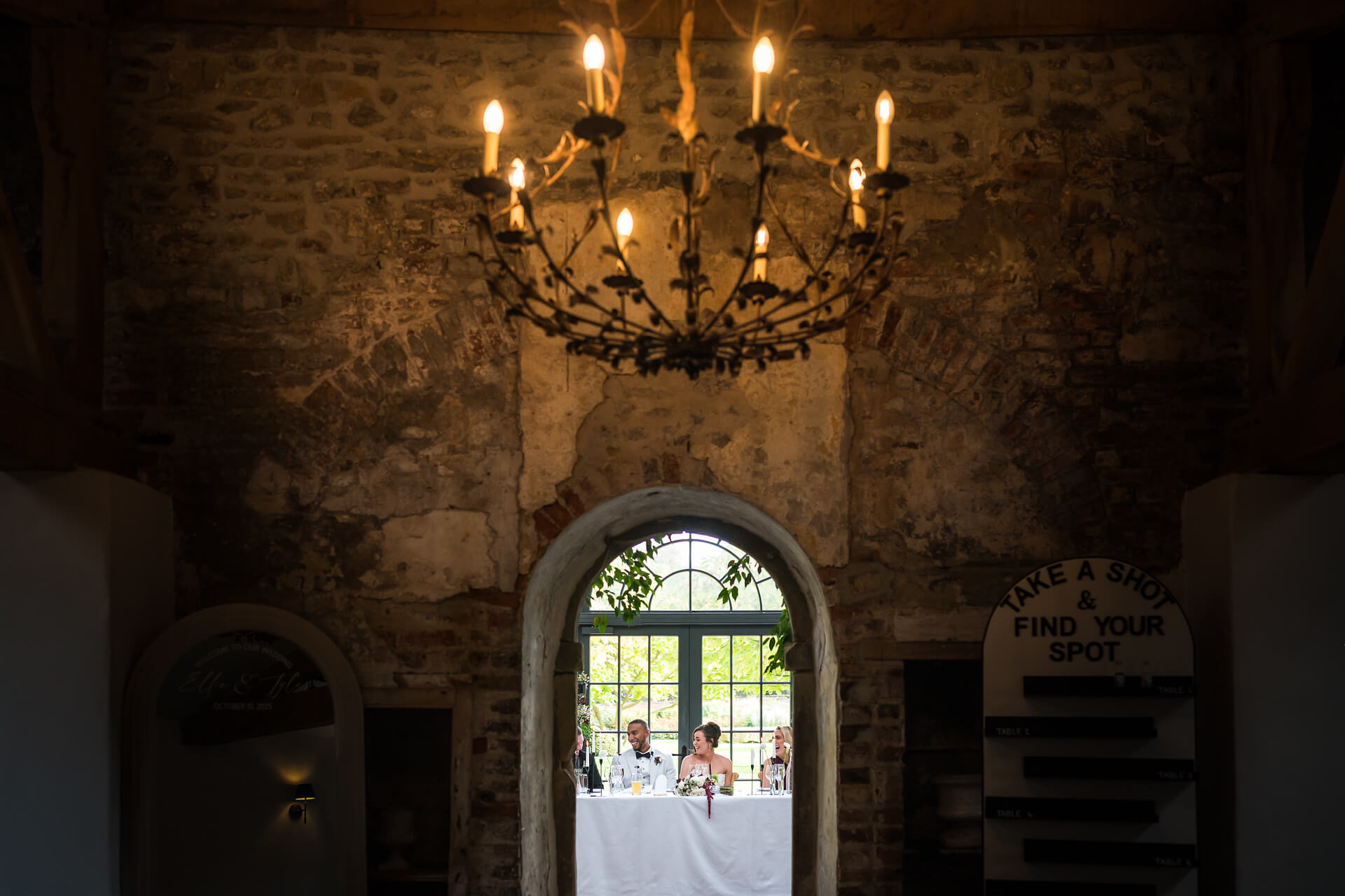 Dining table under rustic chandelier in stone room.