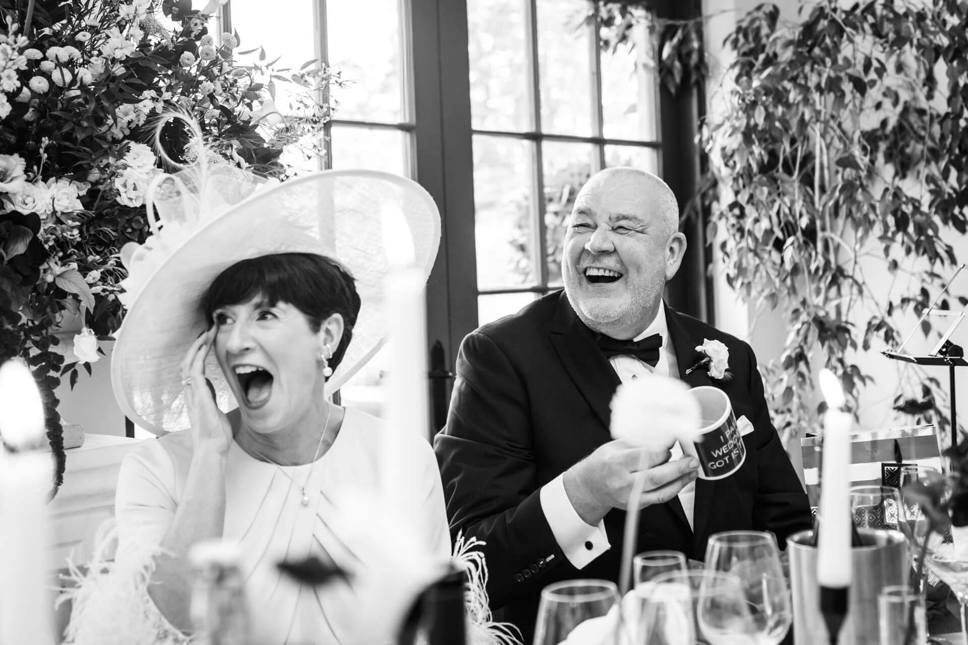 Couple laughing at wedding reception with flowers.