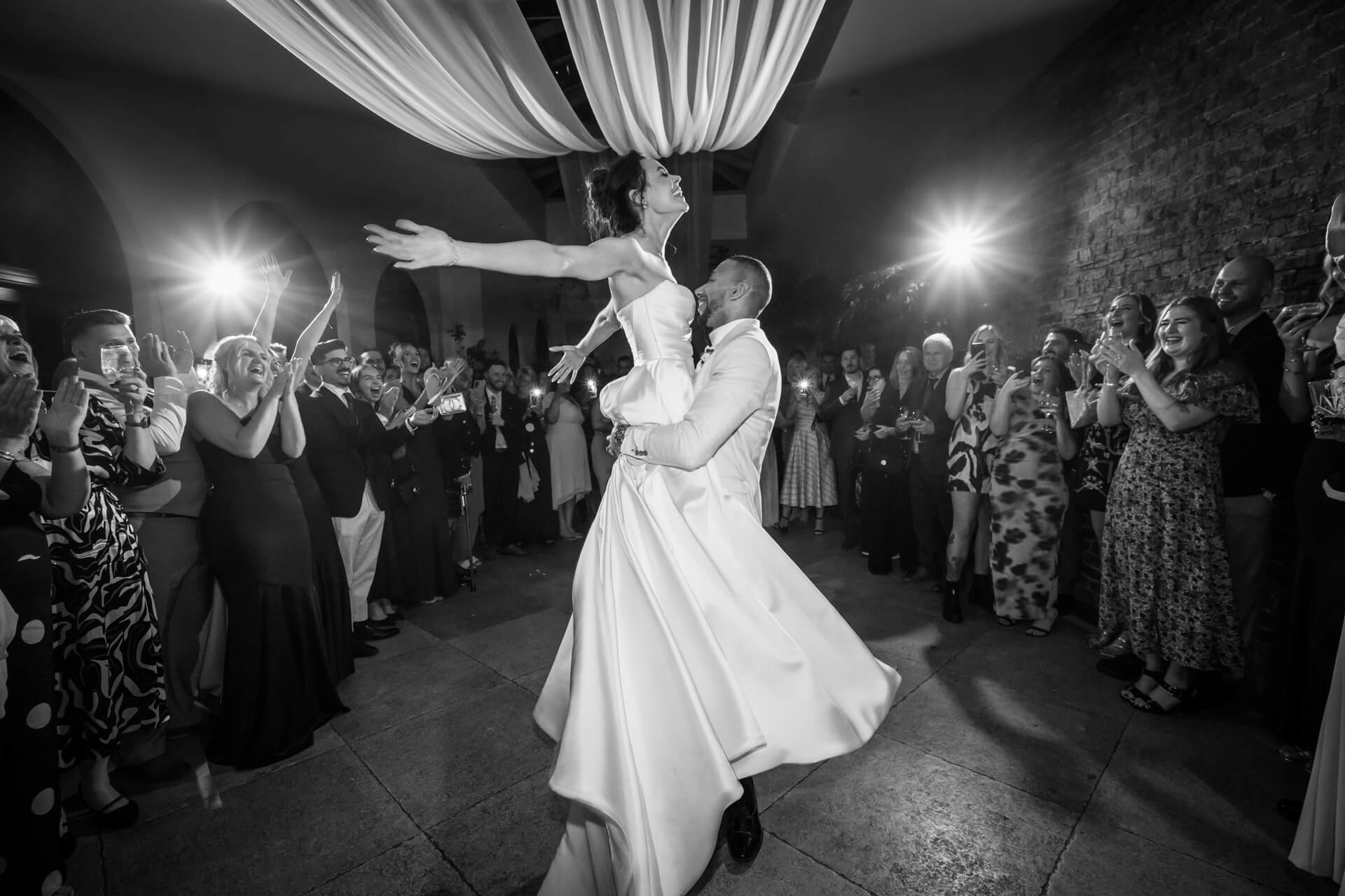 Bride and groom first dance surrounded by guests.