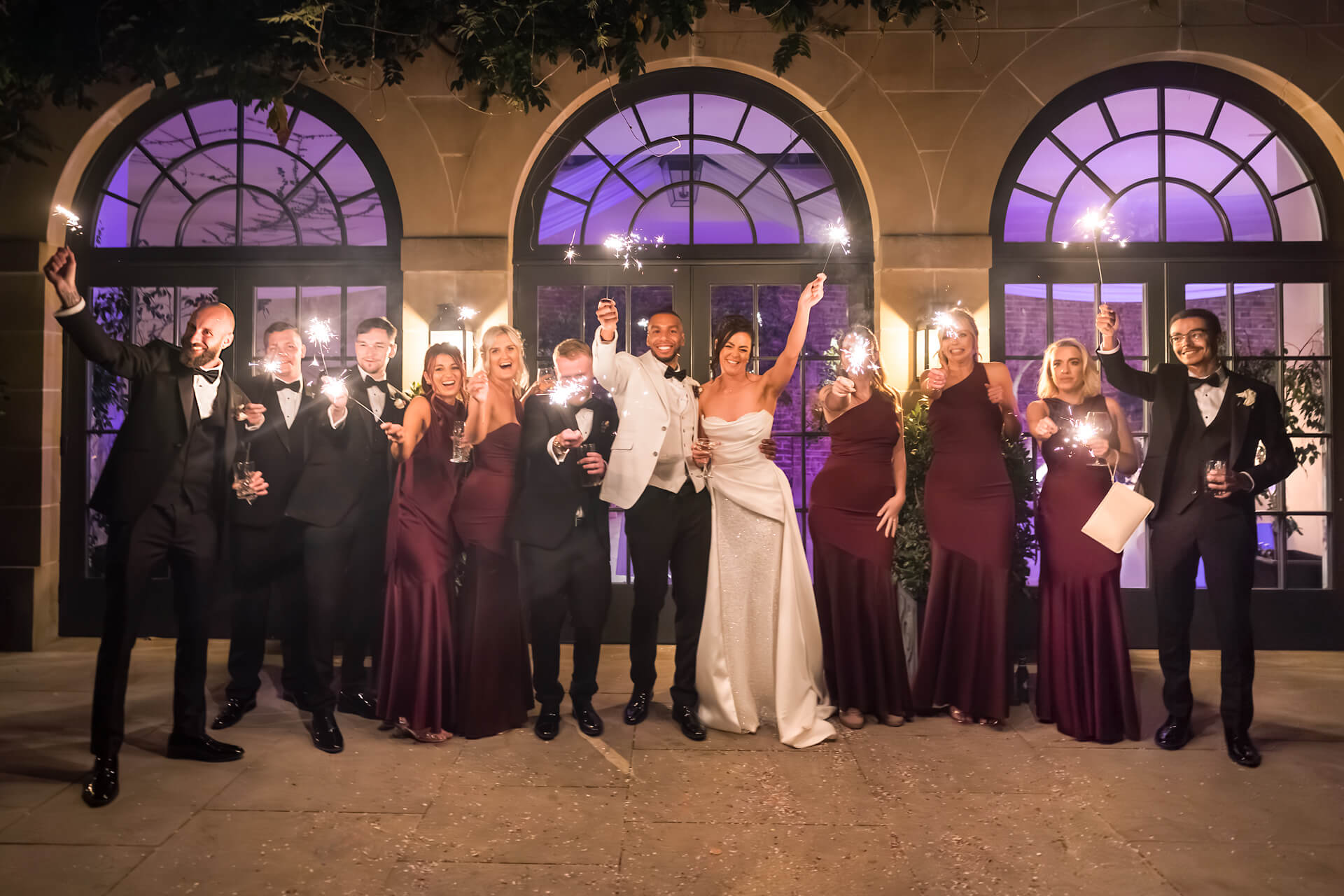 Wedding party with sparklers celebrating outside venue