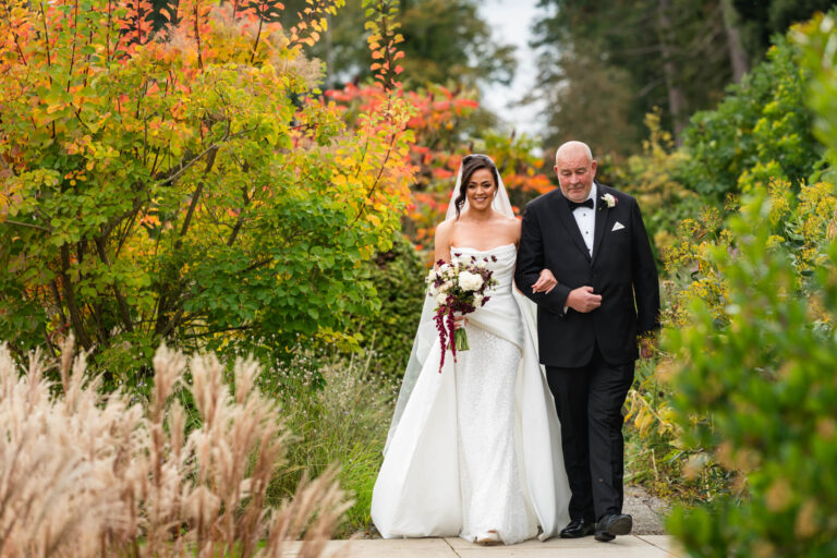 Bride walking down garden aisle with escort.