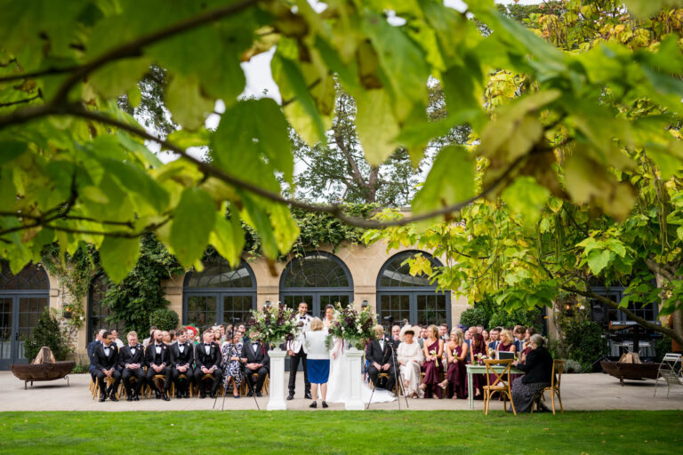 Outdoor wedding ceremony under leafy tree canopy.