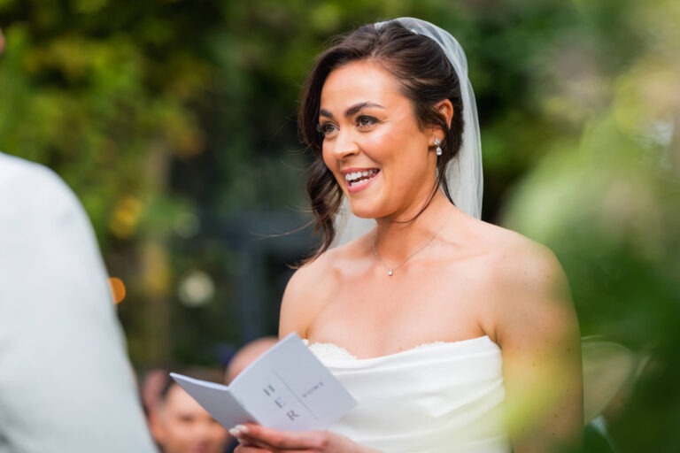 Bride reading vows outdoors, smiling.