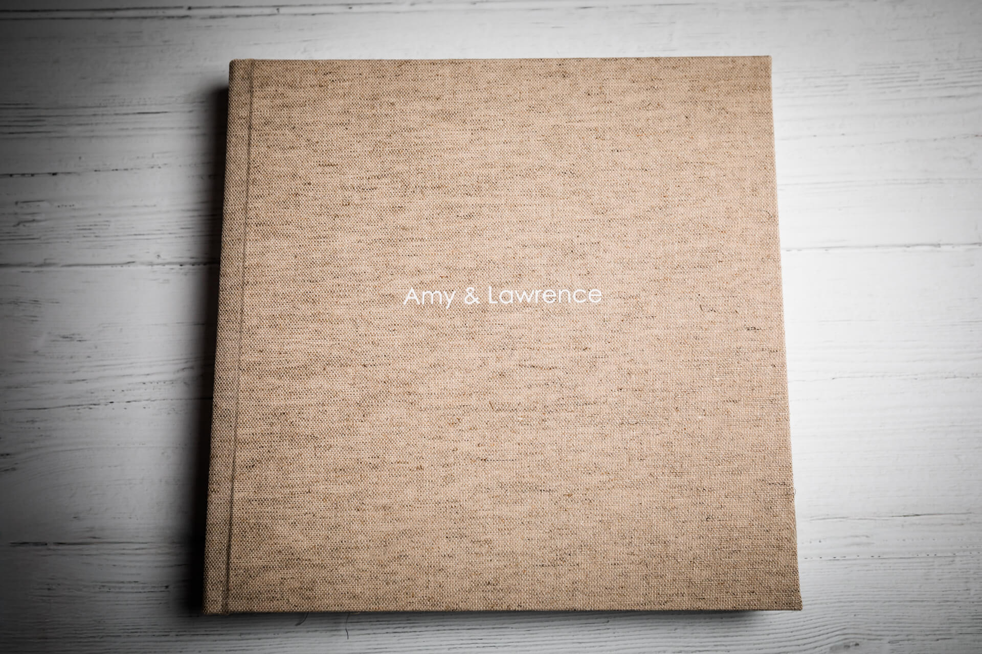 Beige photo album cover on wooden table.