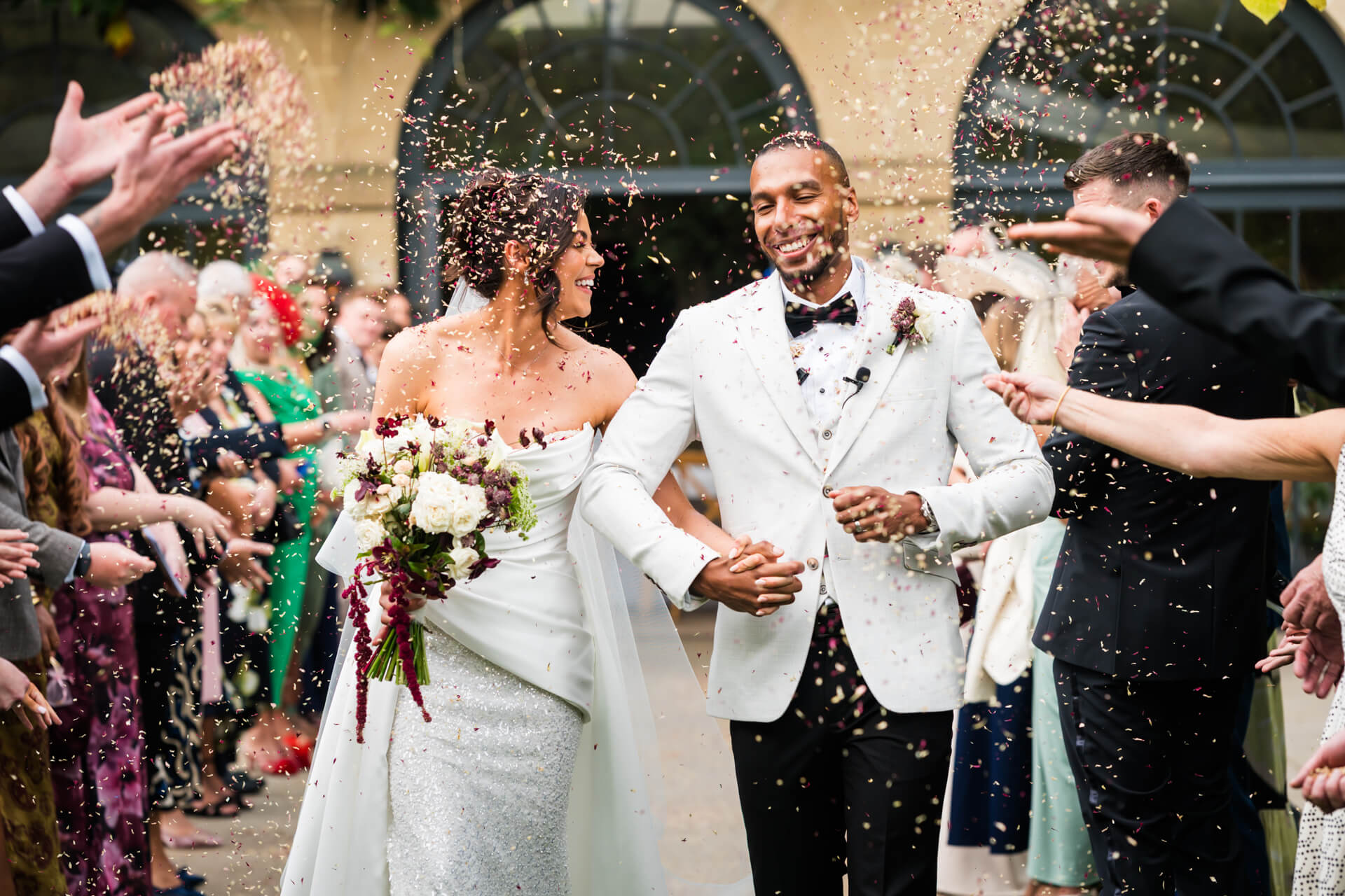 Bride and groom walking through confetti at wedding.