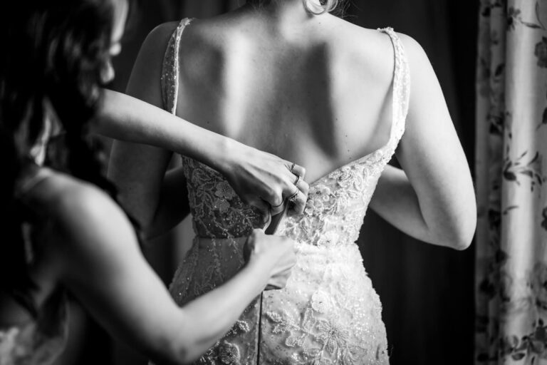 Bride's dress being zipped up on wedding day.