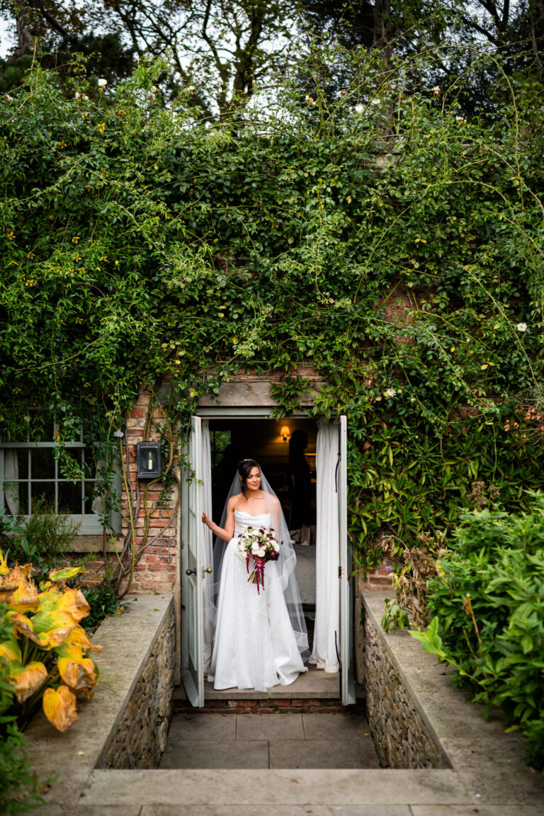 Bride holding bouquet in garden doorway