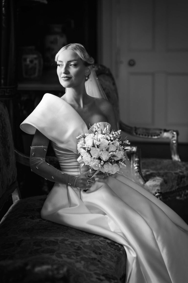 Bride in elegant gown holding a flower bouquet.
