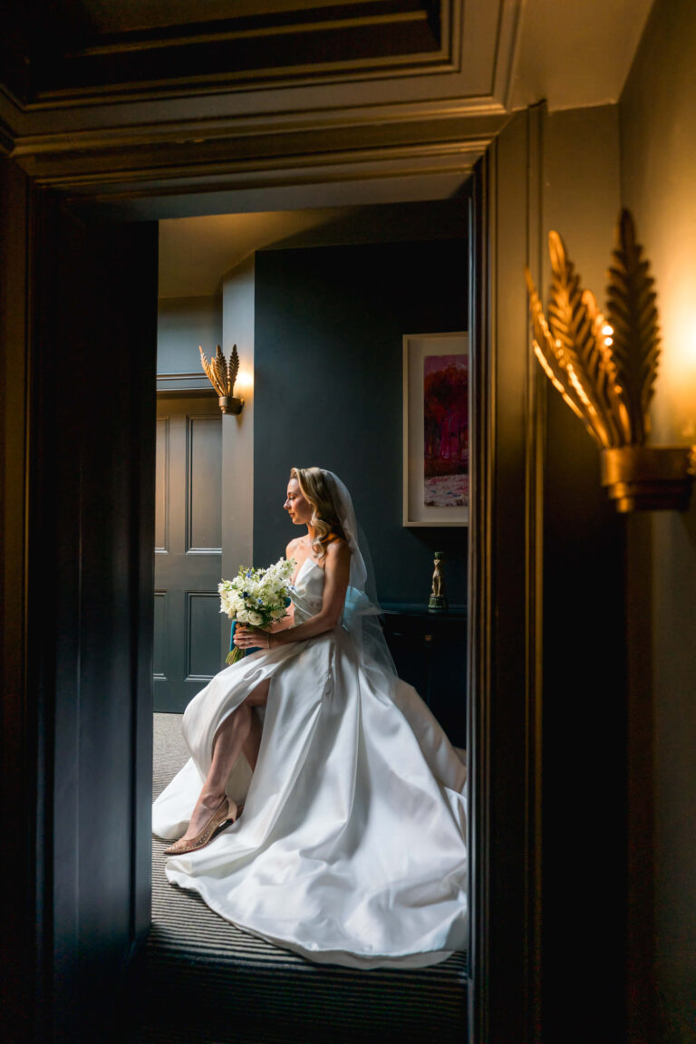 Bride in elegant gown with bouquet indoors.