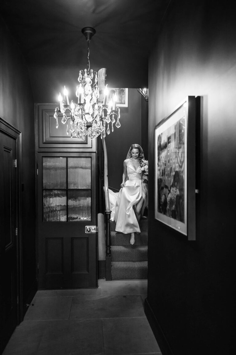 Bride descending staircase in elegant wedding dress.