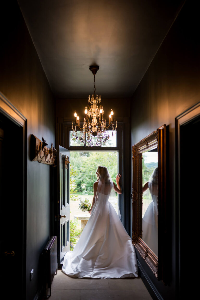 Bride in hallway, looking out the open door.