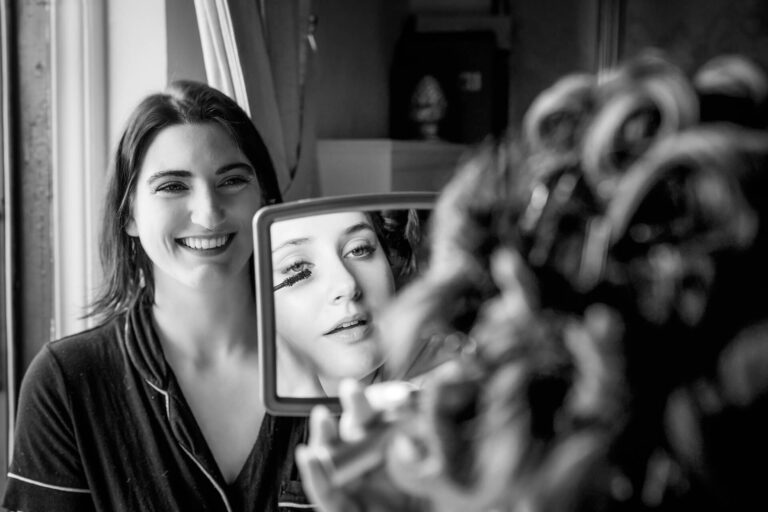 Smiling woman holding mirror during makeup application