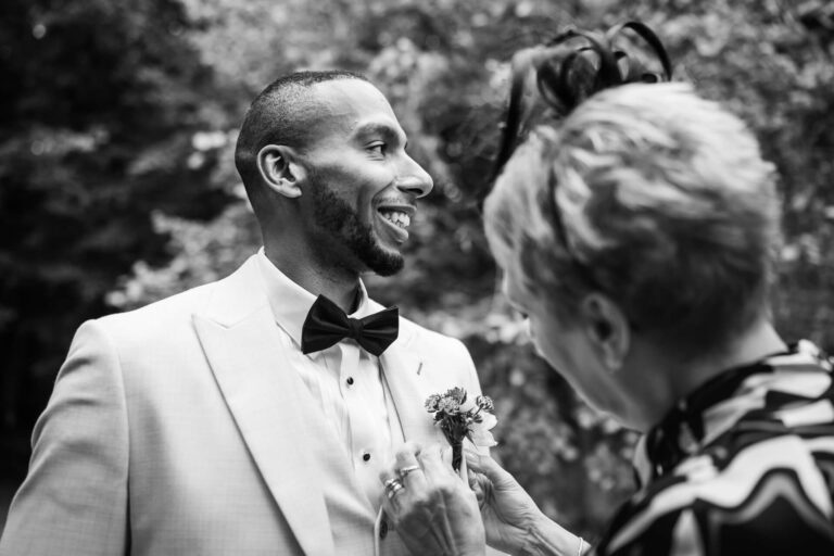 Smiling groom with floral boutonniere, outdoor setting.