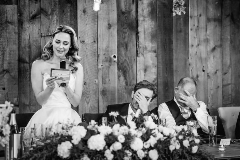 Bride gives speech; guests cover faces humorously.