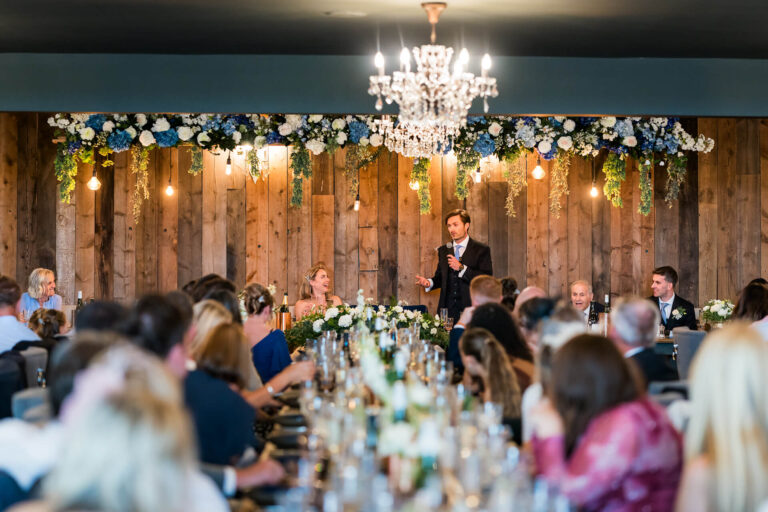 Groom gives speech during rustic-themed wedding reception.