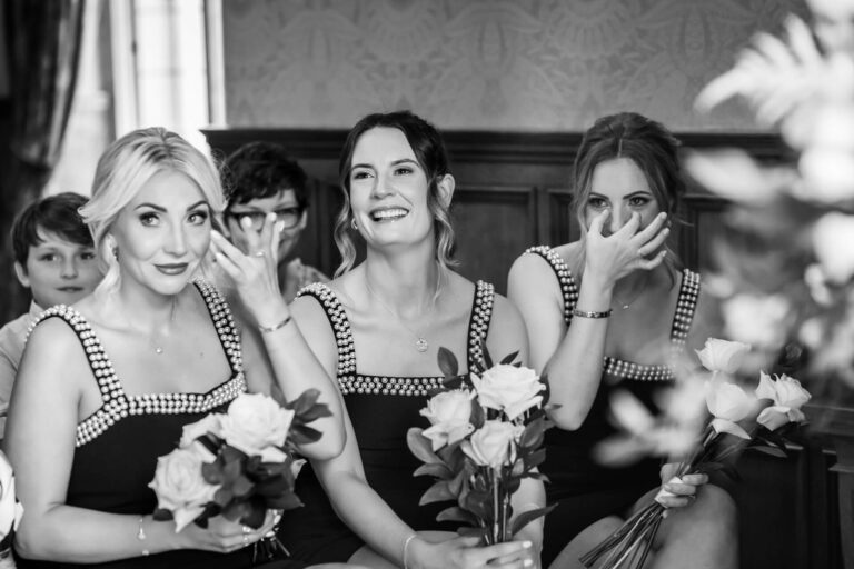 Bridesmaids smile and hold flower bouquets at wedding.