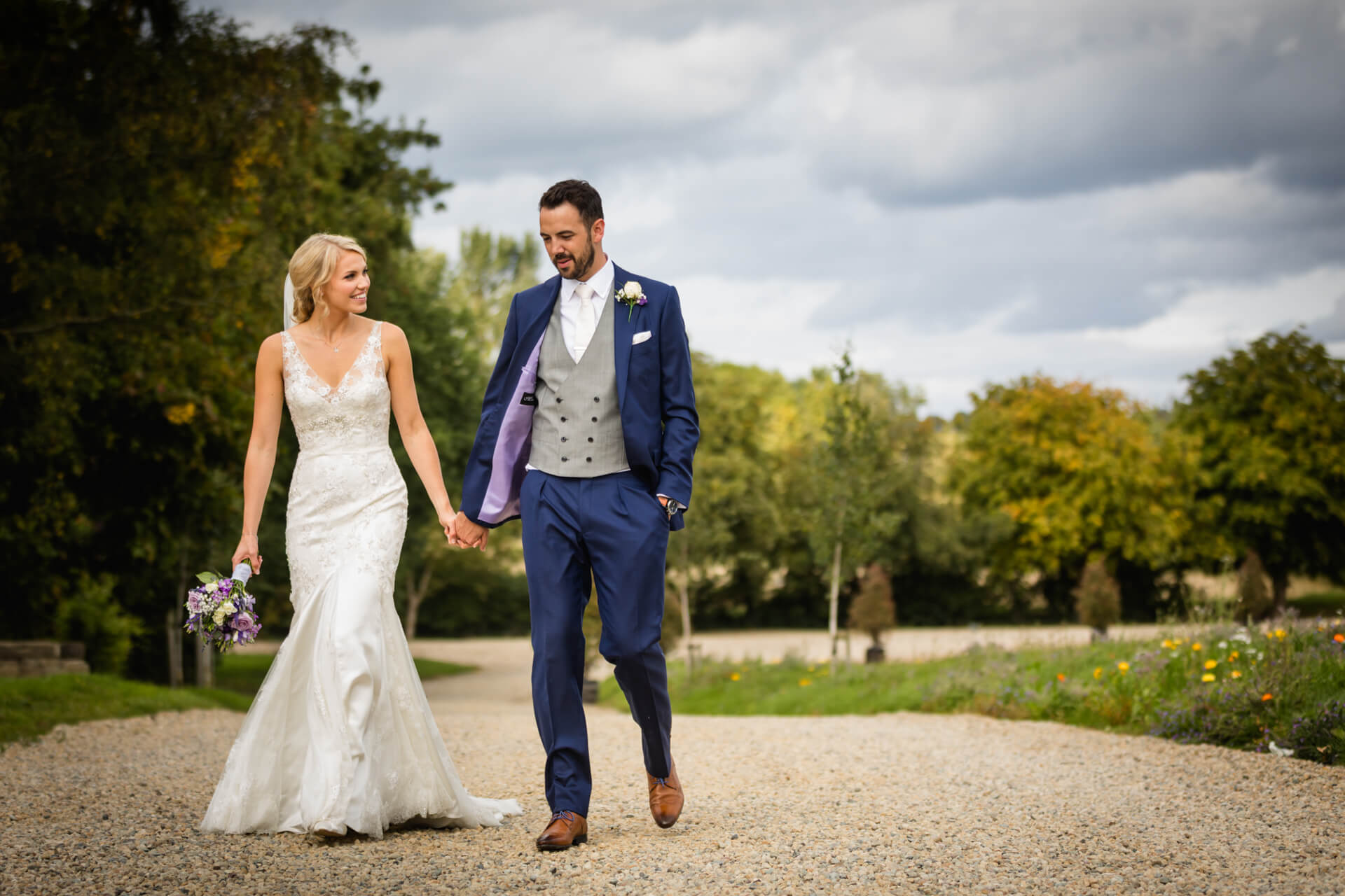Bride and groom walking hand in hand outdoors.